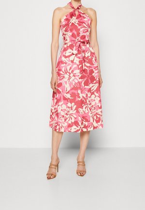 Vestido midi rosa sin mangas con escote halter, estampado grande de flores blancas y cinturón anudado en la cintura, combinado con sandalias de tacón alto color marrón claro.