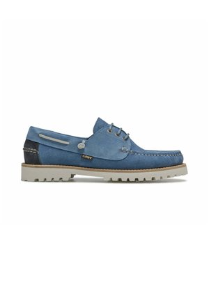Chaussure bateau en daim bleu avec semelle en caoutchouc beige, laçage à l'avant et empiècement de talon foncé contrastant avec détails cousus.