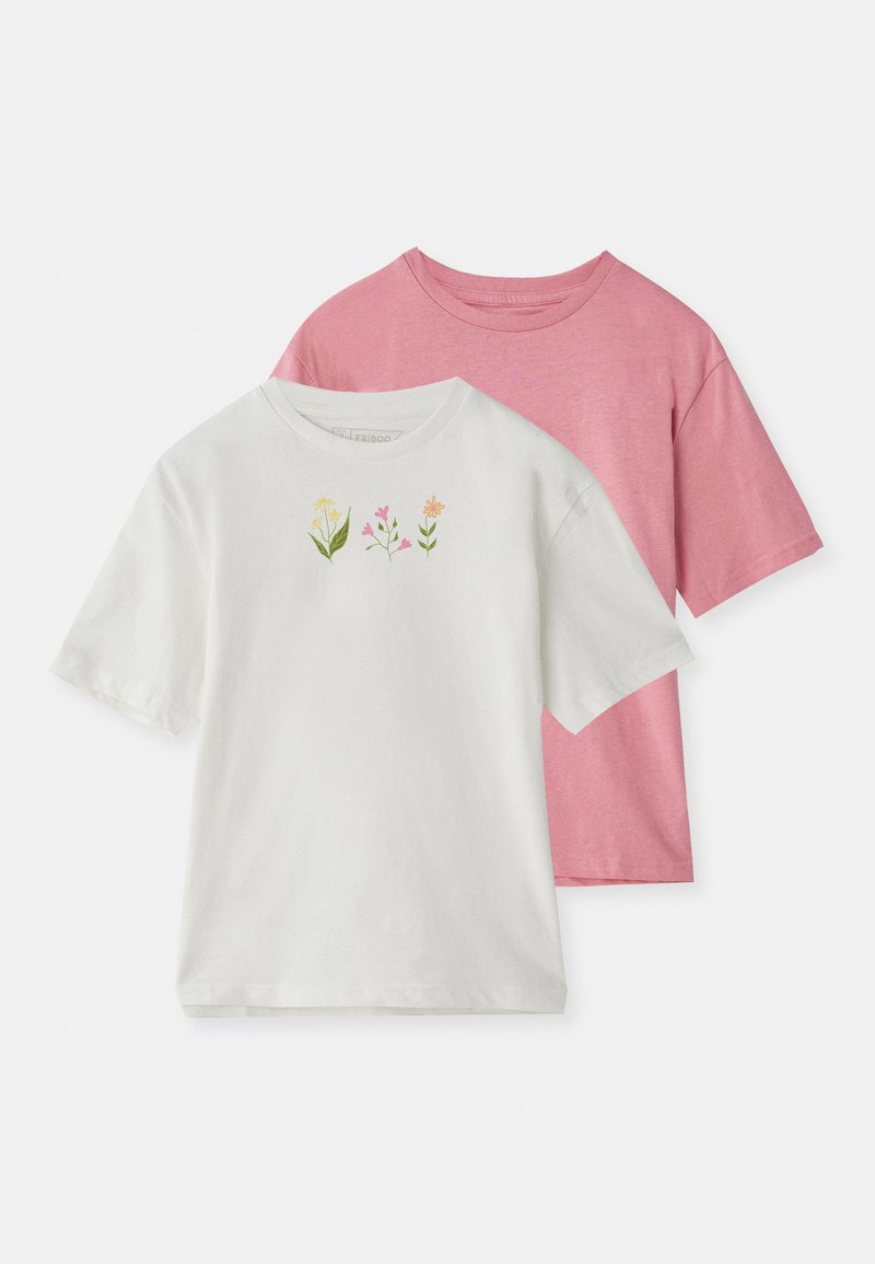 Δύο κοντομάνικα μπλουζάκια τοποθετημένα το ένα πάνω στο άλλο: ένα λευκό με πολύχρωμο κεντημένο λουλούδι στο στήθος και ένα ολόσωμο ροζ. Και τα δύο είναι φτιαγμένα από μαλακό βαμβακερό ύφασμα.