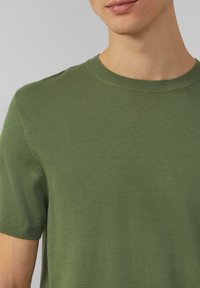 Groen t-shirt met ronde hals, gemaakt van ribbeltricot. Korte mouwen, naadloze schouders en een strakke afwerking bij de hals en mouwen.