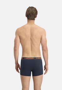 Boxers en coton navy avec une taille élastique arborant un logo orange. Les shorts ont une coupe ajustée et une texture lisse.