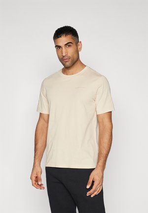 Beige katoenen T-shirt met korte mouwen, ronde hals en subtiele logo-accent op de linkerkant van de borst. Glad textuur; reguliere pasvorm.