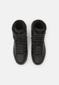 Schwarze High-Top-Schuhe aus glattem Leder mit einem gefütterten Innenleben aus strukturiertem Stoff, ausgestattet mit schwarzen und grauen gemusterten Schnürsenkeln sowie Metallösen.