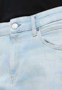 Ανοιχτού μπλε τζιν παντελόνι με κλασικό σχέδιο πέντε τσεπών, που διαθέτει ορατό κουμπί και διακριτές ραφές. Λείος υφασμάτινος χαρακτήρας.