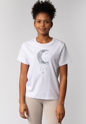 Lichtgrijze katoenen t-shirt met een zwart, halve maan ontwerp met hangende elementen. Eenvoudige ronde hals en korte mouwen.