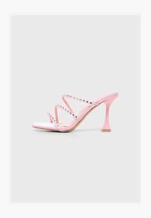 Sandalo rosa con tacco alto con tre sottili cinturini decorati con strass trasparenti e punta quadrata aperta su sfondo bianco.