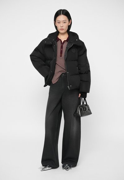 Μαύρο μπουφάν, γκρι πουλόβερ με κουμπιά, φαρδιά μαύρα τζιν και κομψά ασημένια παπούτσια. Μικρό μαύρο τσαντάκι με χερούλια.