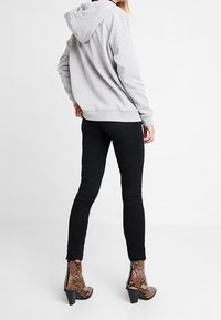 Sudadera gris con capucha de corte relajado, combinada con vaqueros negros ajustados y botines de tacón en estampado de serpiente marrón.