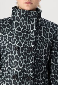 Cappotto leopardato con colletto alto, design a doppio bottone, realizzato in tessuto morbido, con una base nera e macchie grigie e turchesi.