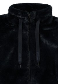 Veste en fausse fourrure zippée bleue marine avec un col montant, dotée de cordons de serrage noirs avec texte imprimé et d'une texture lisse.