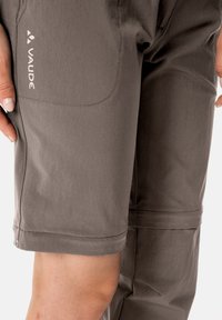 Graue Shorts aus leichtem Stoff mit glatter Textur, versehen mit einer Seitentasche und dem weißen "VAUDE"-Logo.