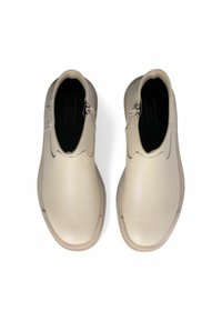 Stivali ankle in pelle beige con una texture liscia, pannelli laterali elastici e un sottile dettaglio del logo sul retro. Punta rotonda, suola piatta.