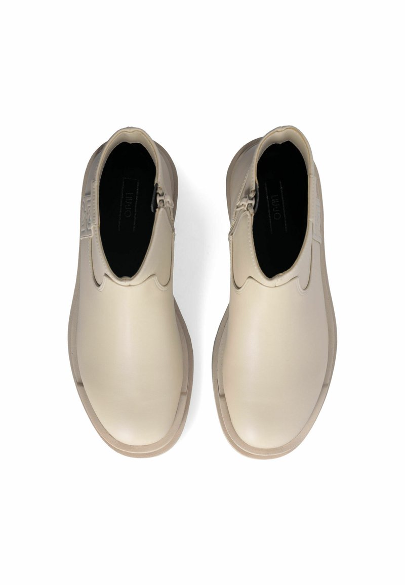 Beige Leder-Stiefeletten mit glatter Textur, elastischen seitlichen Einsätzen und einem dezenten Logodetail auf der Rückseite. Rund zulaufende Zehenpartie, flache Sohle.