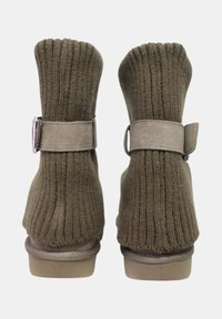 Stivaletti alla caviglia marroni in maglia con texture a costine, una cinghia color cuoio con fibbia e una suola spessa. Vista posteriore che mostra il design superiore a calzino.