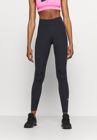 Czarne legginsy z wysokim pasem, wykonane z elastycznego, gładkiego materiału. Posiadają małe białe logo Nike na dolnej części lewego nogawki.