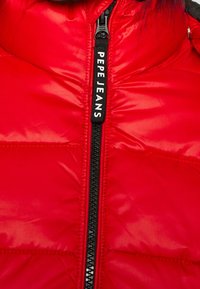 Röd puffjacka med texturerad yta, en svart dragkedja med "PEPE JEANS"-logotyp och ståkrage.