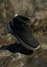 Bota de caminhada preta com parte superior em sintético, design texturizado, fecho de atacadores e sola de borracha clara. Apresenta logo na lateral.