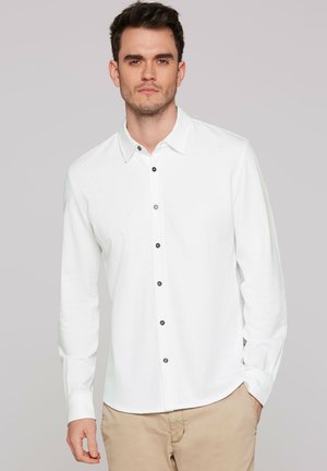 Weißes Langarmhemd aus Baumwolle mit durchgehender Knopfleiste, dunklen Knöpfen, spitzem Kragen und lockerem Schnitt.