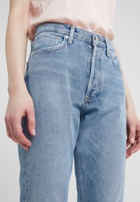 Světle modré džíny z denimu s vysokým pasem, rovnými nohavicemi a klasickým pětipocket designem, s jemným vyblednutím a detaily v šití.