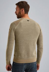 Olijfgroen gebreide trui met een gestructureerde stof, slim fit ontwerp, geribde manchetten en zoom, met een zak op de linker schouder.