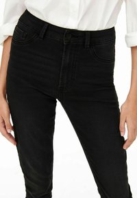 Svarta högmidjade jeans med en slät denimtextur, med frontfickor, knappstängning och en slim-fit design.