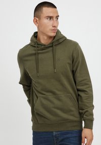 Olive green hoodie made of soft fabric, featuring a kangaroo pocket, adjustable drawstrings, and a small logo on the chest.