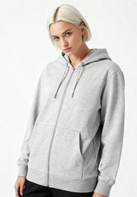 Felpa grigia con zip, dotata di cappuccio regolabile con cordino, tasche frontali, polsini e orlo a coste, e un tessuto morbido e texture.