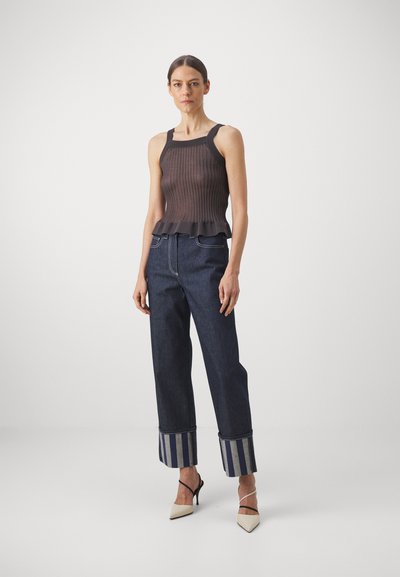 Dark ribbed tank top with ruffled hem, paired with wide-leg dark denim jeans featuring striped cuffs and pointed-toe heels.