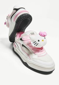 Białe i różowe sneakersy z siateczkową górą, teksturowaną gumową podeszwą i pluszowym akcentem Hello Kitty na języku. Różowe detale na sznurowadłach.