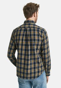 Geruite shirt in marineblauw, geel en wit. Bevat een knoopsluiting bij de kraag, lange mouwen en een relaxte pasvorm. Gemaakt van zacht stof met een plooi aan de achterkant.