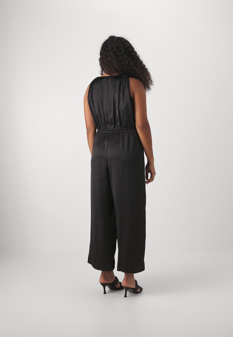 Mono de satén negro con un corte relajado, diseño sin mangas, cintura elástica, pierna ancha y textura suave. La vista trasera muestra un estilo sencillo.