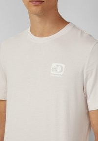 Lichtgrijs t-shirt met een ronde hals, korte mouwen en een witte bedrukte logo met een wereldbol en het woord "Discovery" op de borst.