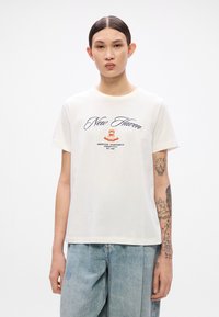 White short-sleeve t-shirt made from cotton, featuring "New Haven" in navy script and an emblem with red crown and text on the chest.