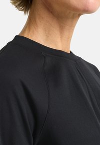Schwarzer Sportpullover mit geripptem Textur, Rundhalsausschnitt und gestickten Details entlang der Schultern und Seitennähte.