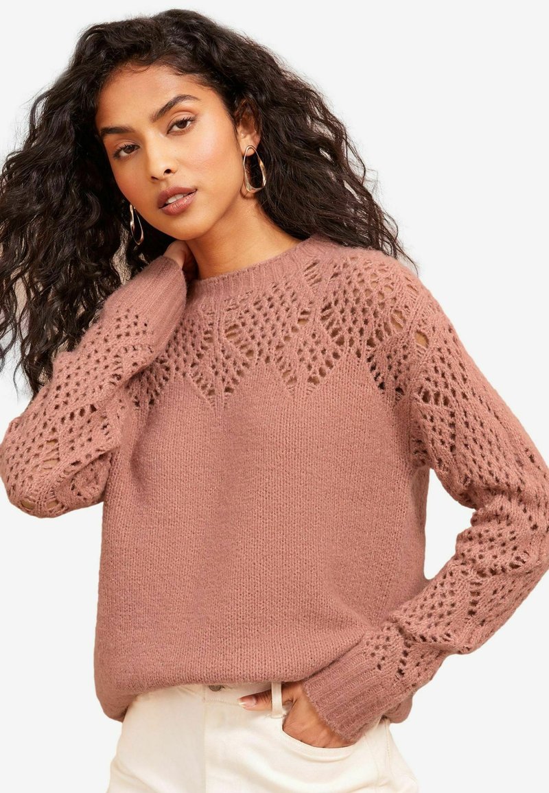 Rosenfarbener Strickpullover mit lässiger Passform, der komplizierte Spitzendetails an den Ärmeln sowie einen gerippten Hals- und Ärmelsaum aufweist.