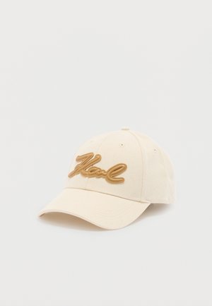 Beige baseball cap with curved brim featuring raised cursive text "Karl" in tan on the front.