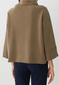 Avskuren, olivgrön sweatshirt med hög krage och vida ärmar, med en mjuk textur och enkel, ren design.