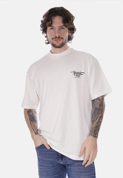 T-shirt bianco in cotone con una vestibilità comoda, maniche corte e scollatura rotonda. Presenta una piccola stampa grafica nera sul petto.