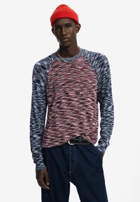 Pikad varrukad, ümar kaelusega särk, millel on punane ja tumesinine marli muster, kontrastsete raglan varrukatega ja mugav lõige.