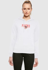 Hoodie bianco con grafica "PEACHES" in rosso, caratterizzato da un'illustrazione di una pesca. Tasca a marsupio, cordini e polsini a costine.