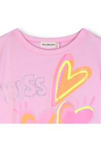 Ροζ κοντομάνικη μπλούζα με την επιγραφή "KISS" από στρας και πολύχρωμες καρδιές σε κίτρινο και πορτοκαλί. Απαλό βαμβακερό ύφασμα, στρογγυλή λαιμόκοψη.