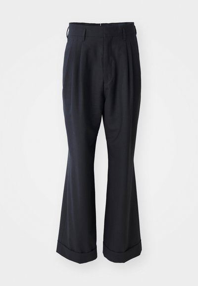 Pantalons noirs ajustés avec une coupe décontractée, devant plissé et jambes larges. Caractéristiques d'un ourlet à retournement et d'une texture de tissu lisse.