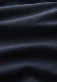 Donkerblauwe stof met een gladde structuur, met subtiele diagonale ribbeltjes. Het materiaal oogt licht en zacht.