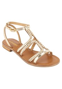 Sandali con cinturino intrecciato in oro, con tacco piatto in legno e soletta color tan. Presentano una fascia regolabile alla caviglia e un design open-toe.