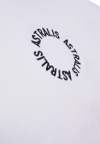 Vit bomull t-shirt med rund svart brodyr av ordet "ASTRALIS" som upprepas i ett cirkulärt mönster. Mjuk textur, avslappnad design.