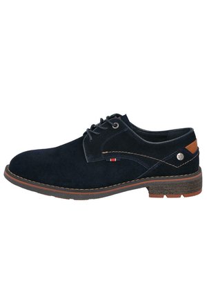 Zapato de ante azul marino con un detalle marrón en el talón, costuras de contraste y una suela de goma texturizada. Presenta un pequeño detalle del logo.