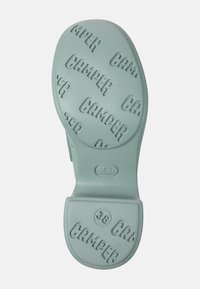 Mintgroene rubberen zool met verhoogde "CAMPER" tekst. Afgeronde hak met een afgeronde neus en logodetails. Maat 38 gemarkeerd op de hak.