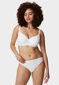Reggiseno bianco con design liscio e spalline regolabili, con sottili dettagli in pizzo sulla fascia, abbinato a slip bikini bianchi coordinati.