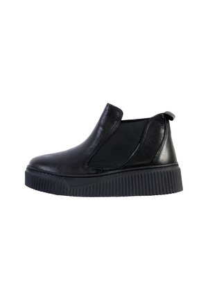 Chaussures noires en cuir à enfiler avec des panneaux élastiques sur les côtés et une semelle en caoutchouc noir texturé. Matière supérieure lisse et design minimaliste.