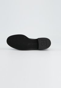 Zwarte platte schoen zool met een getextureerd rubber oppervlak. Voorzien van subtiele logo-details en een soepele, contoure vorm voor comfort.